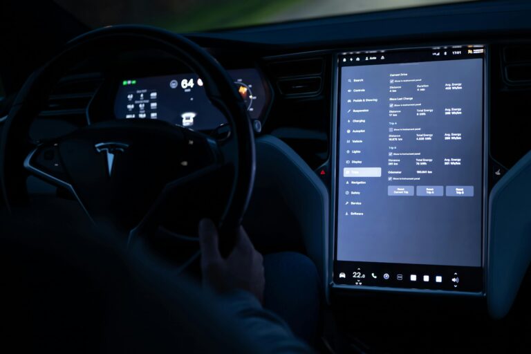 Interior view of an electric car showing advanced touchscreen and steering wheel at night.